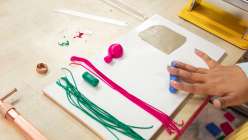 Multicolored earrings being made by Faheema Chaudhury in her Make Faux Knit Dangle Earrings with Polymer Clay class on Creativebug.