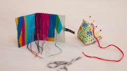 A colorful needle book and pin cushion made in Rebecca Ringquist's Make a Pin Cushion and Needle Case class on Creativebug.