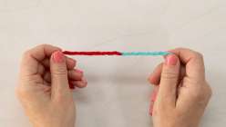 A pair of hands showing a join between a teal and a red piece of yarn from Twinkie Chan's Invisible Yarn Joins for Knit and Crochet class on Creativebug.