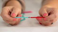 A pair of hands showing a join between a teal and a red piece of yarn from Twinkie Chan's Invisible Yarn Joins for Knit and Crochet class on Creativebug.