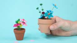 Two small terracotta pots with quilled flowers made in Nikki Furlong's Paper Quill Mini Potted Flowers class on Creativebug