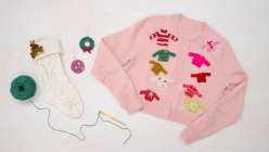 A white stocking, crocheted ornaments, and a pink sweater covered in crocheted mini sweaters made by Twinkie Chan in her Holiday Crochet Applique class on Creativebug