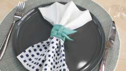 A white napkin with a turquoise leather napkin ring made in the Make Leather Napkin Rings class on Creativebug