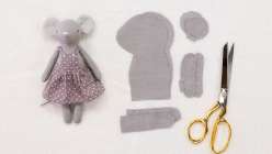 A small grey mouse doll wearing a dress, made in Katia Ferris's Sew a a Mouse Doll class on Creativebug 