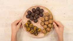 A pair of hands holding a plate of bliss balls in Cobrina's Creativebug class Bliss Balls: 3 Recipes for Snacking.