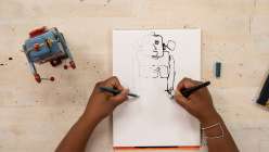 A toy robot being drawn with both hands simultaneously by e bond in her Drawing Disrupted: 15 Experiments class on Creativebug.