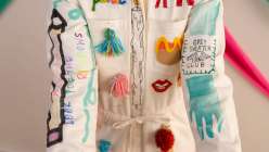 A colorful white jumpsuit embellished with tassels, hand-carved stamps, embroidery, painting, and drawings by Risa Iwisaki Culbertson in her class Wearable Wins on Creativebug